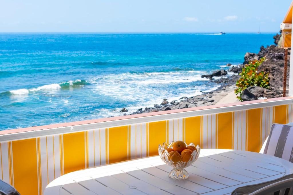 a bowl of fruit on a table on a balcony overlooking the ocean at Neptuno Ocean View, Beach line with Pool in Puerto de Santiago