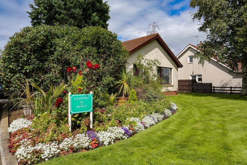 a house with a sign in a flower garden at Cloyfin B and B in Coleraine