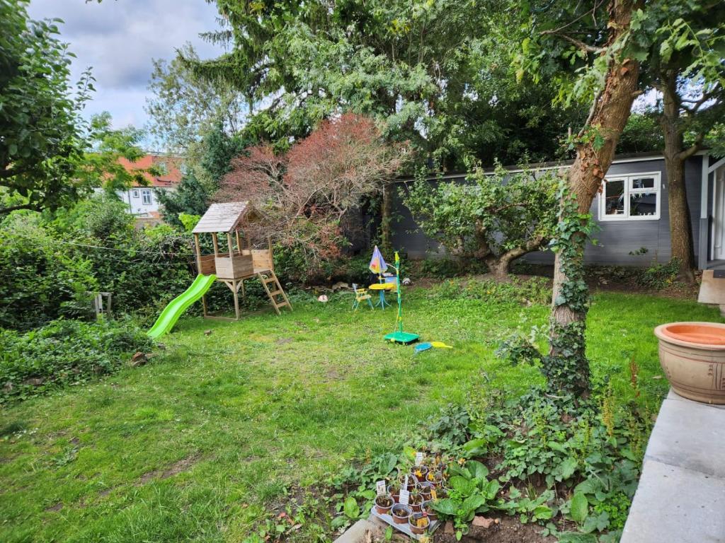 a yard with a playground and a green slide at Spacious Room with Garden in Croydon London in South Norwood