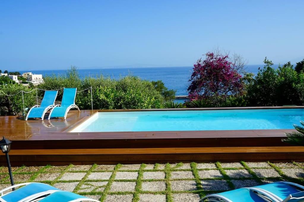 a swimming pool with chairs and the ocean in the background at Villa capri con giardino e piscina in Capri