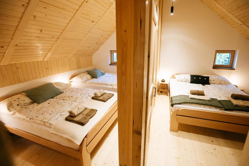 two beds in a room with wooden ceilings at Alpine Cottage Golica in Jesenice