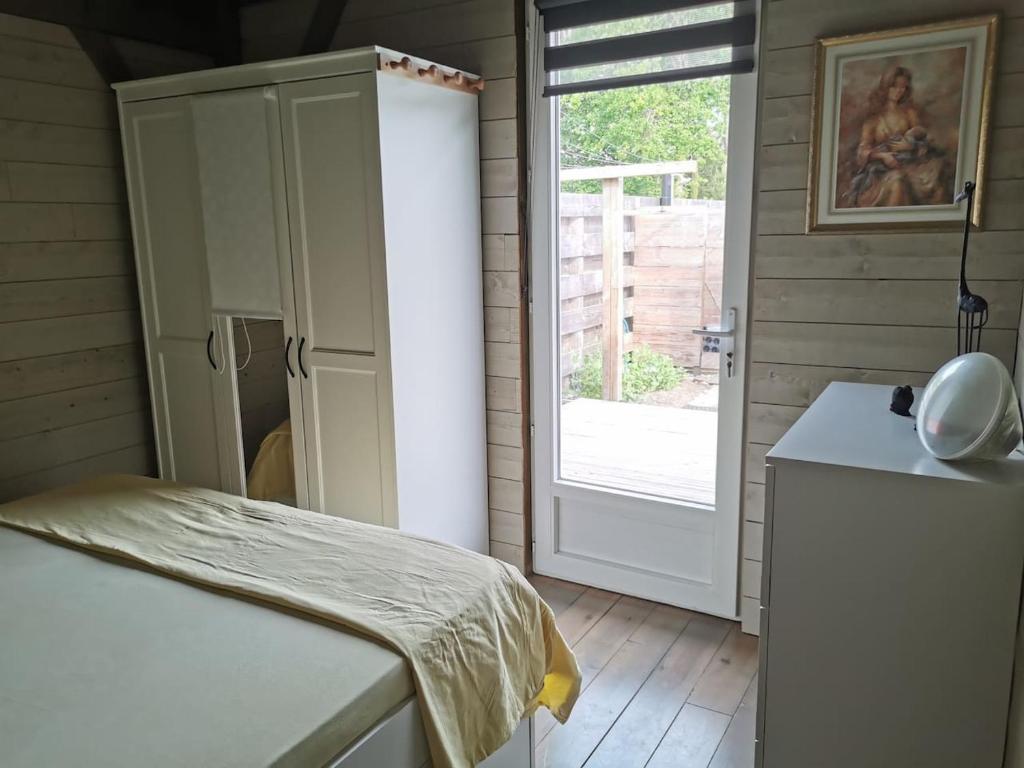a room with a bed and a door to a yard at MAISON &amp; PISCINE PRIVES,PLAGES OCEAN ET LAC A 10 kms in Linxe