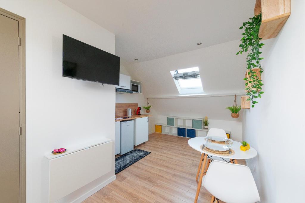 a living room with a table and a kitchen at Malaka Home Anzin in Anzin