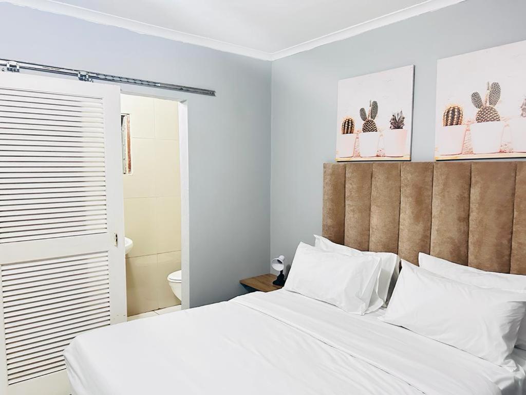 um quarto com uma cama branca e almofadas brancas em Decent Stay em Durban