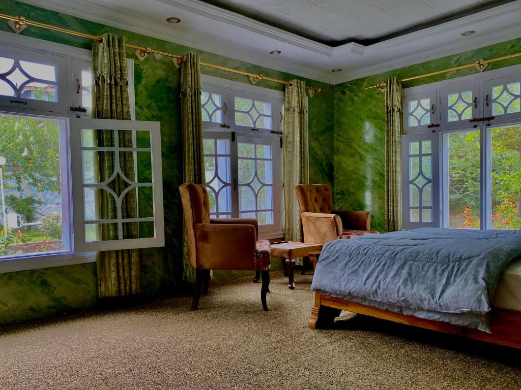 a bedroom with green walls and windows and a bed at Taaj Residence Skardu in Skardu