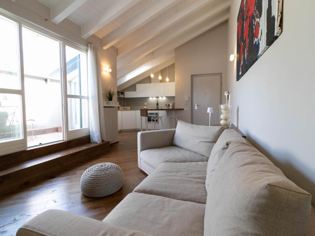 uma sala de estar com um sofá e uma grande janela em Mamma Ciccia Holiday Home - Cozy Attic em Galbiate