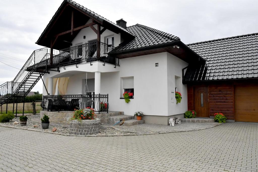 a white house with a balcony on top of it at Apartament u Joli in Miejsce