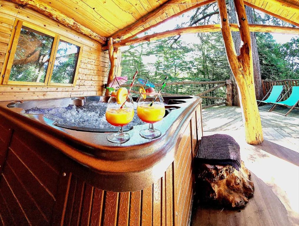 two drinks on a hot tub in a cabin at Domaine de la Font Vineuse & Spa in Saint-Pierre-dʼArgençon