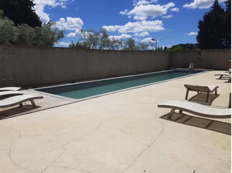 une piscine avec deux bancs à côté d'une clôture dans l'établissement Les Madones, à Nîmes