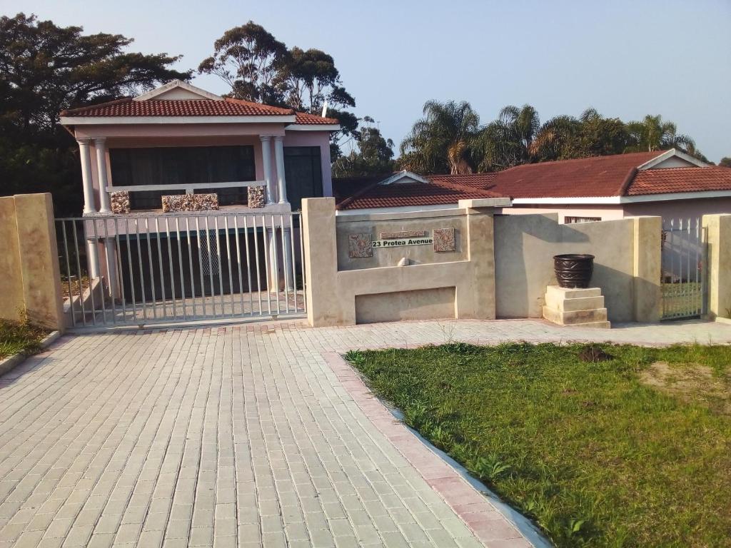 uma casa com uma cerca branca e uma entrada em Protea Avenue Margate em Margate