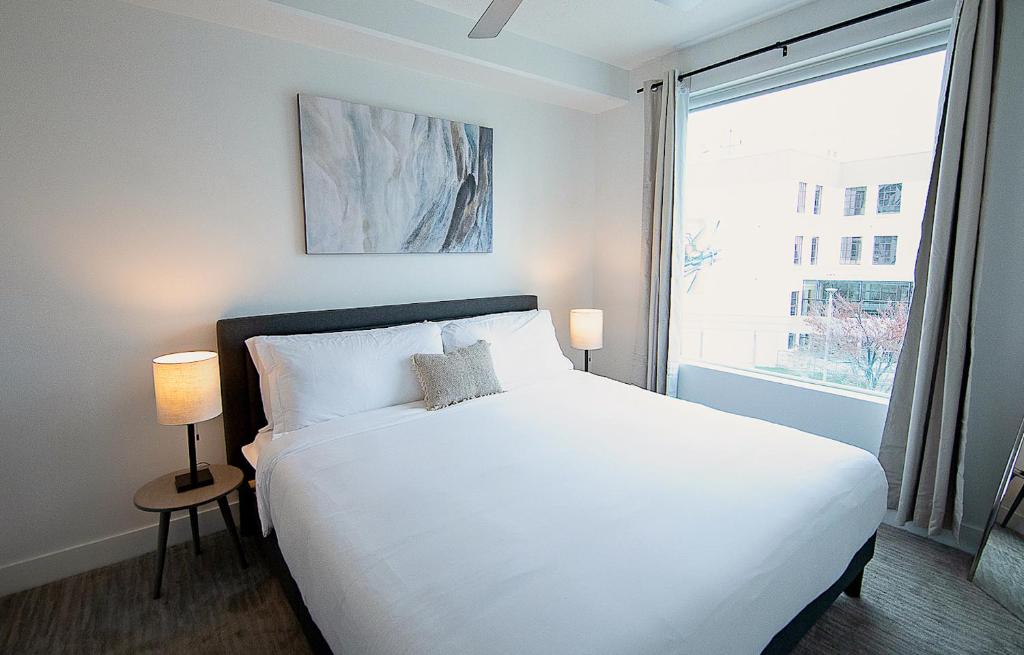 a bedroom with a white bed and a large window at Kasa Downtown Salt Lake City in Salt Lake City
