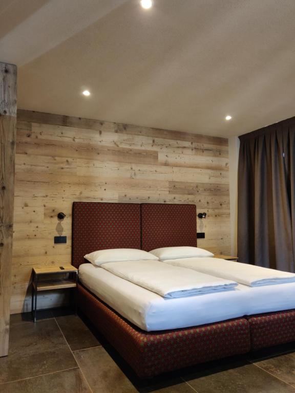 a large bed in a room with a wooden wall at BAITA LARIX BORMIO in Bormio