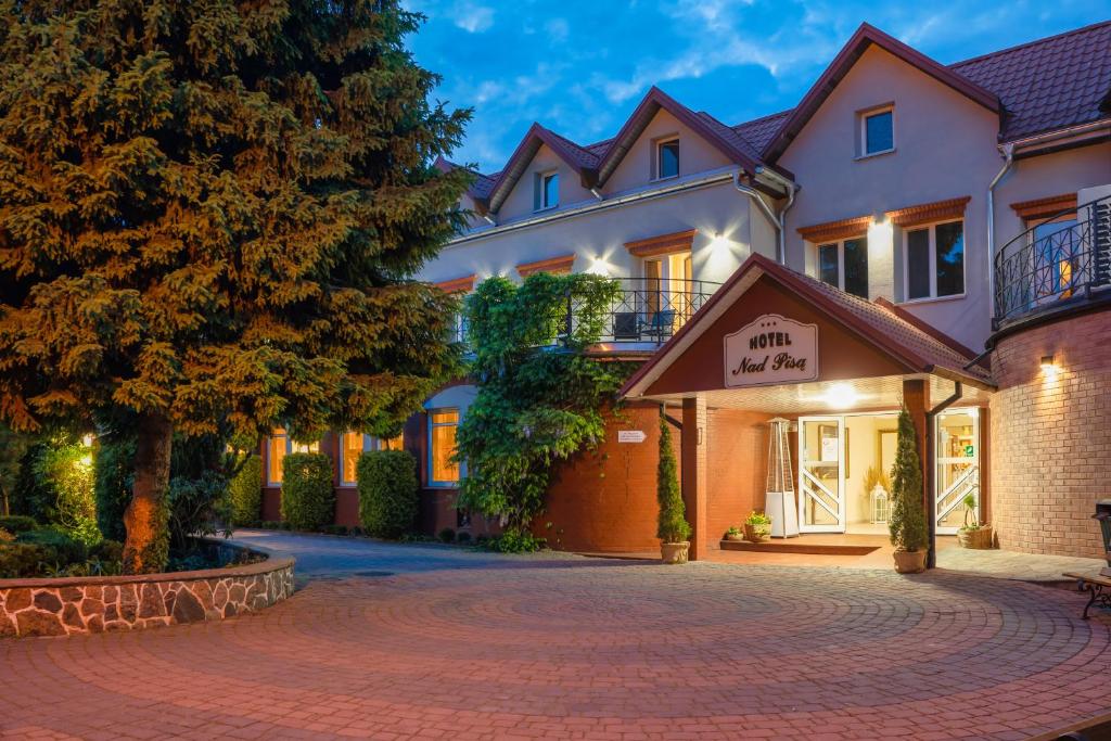 a hotel with a driveway in front of a building at Hotel Nad Pisą in Pisz