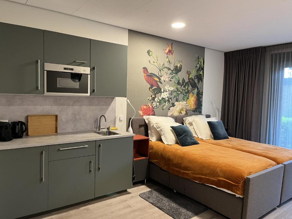 a bedroom with a bed and a kitchen with a microwave at Gasthuis Sanitatem in Putten