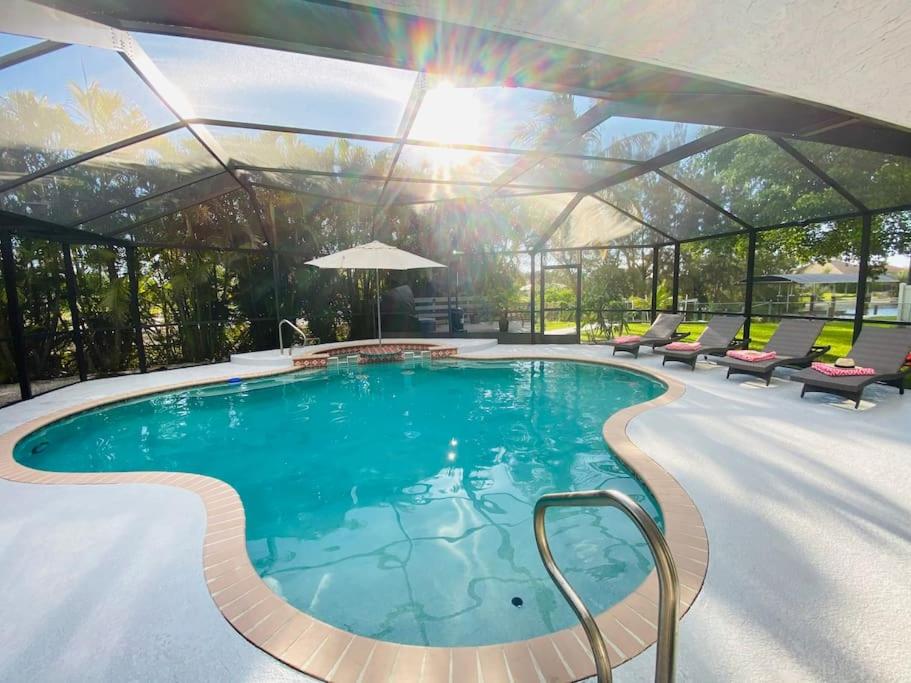 een zwembad met een glazen serre met stoelen eromheen bij Casa de Emma - a 3-bed gulf access vacation home in Cape Coral