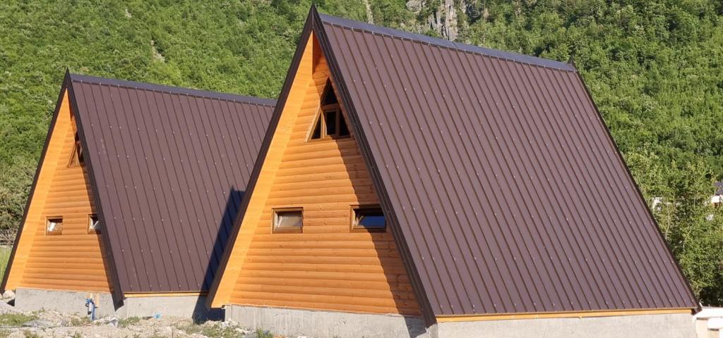 une grande maison en bois avec un toit marron dans l'établissement Bungaja Chalets, à Shkodër