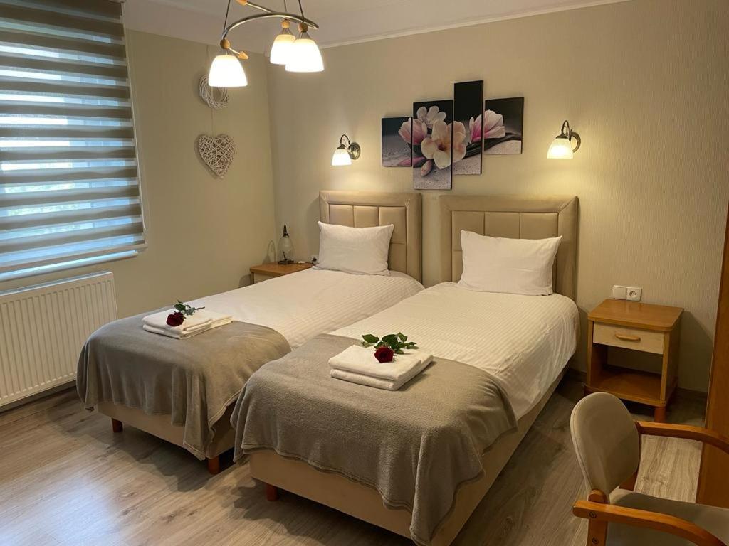 sypialnia z dwoma łóżkami z ręcznikami i kwiatami na nich w obiekcie Villa Regina - Spokojna okolica - 100 metrów od lasu w Kościerzynie