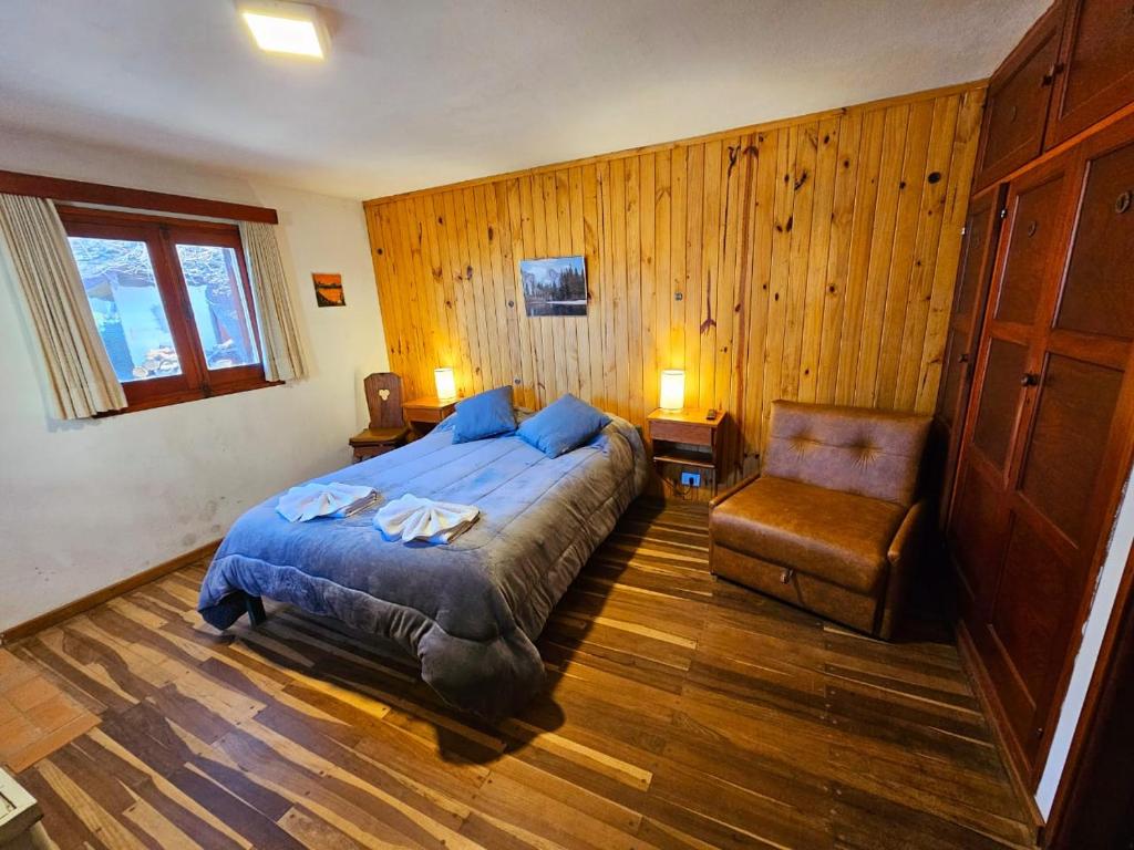 a bedroom with a bed and a chair in it at Hotel La Cumbrecita in La Cumbrecita