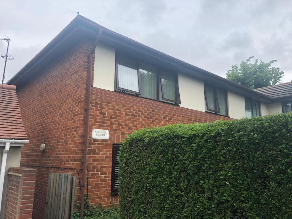 a brick house with a hedge in front of it at Spencer Court in Hornchurch