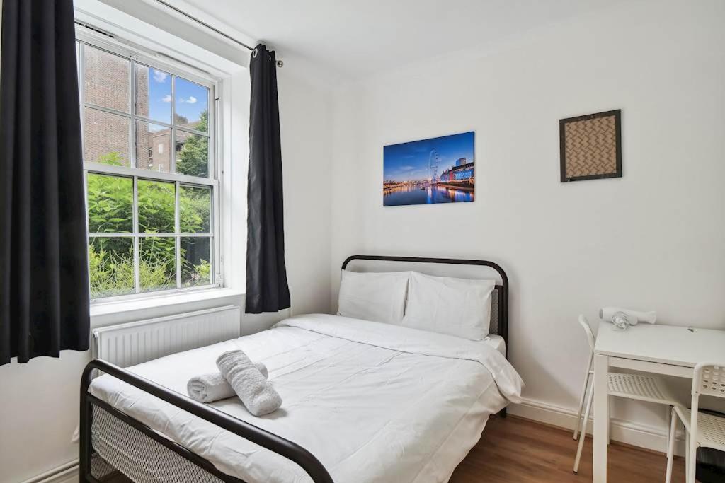 een slaapkamer met een bed, een bureau en een raam bij APlaceToStay Central London Apartment, Waterloo (UPT) in Londen