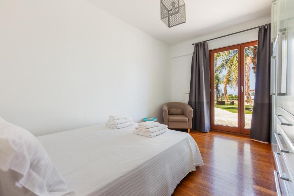 a white bedroom with a bed and a sliding glass door at Angels Villa in Kambánion
