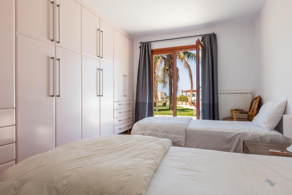 a white bedroom with two beds and a window at Angels Villa in Kambánion