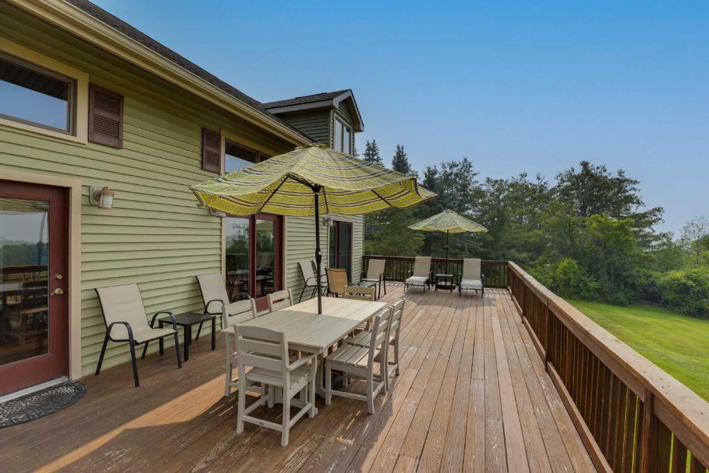 eine Terrasse mit einem Tisch, Stühlen und einem Sonnenschirm in der Unterkunft Spacious Hammondsport Home on 6 Acres with Lake View in Hammondsport