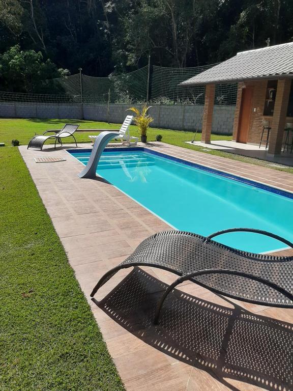 a swimming pool with two chairs next to at Chalés Bem-me-quer Itaipava in Itaipava