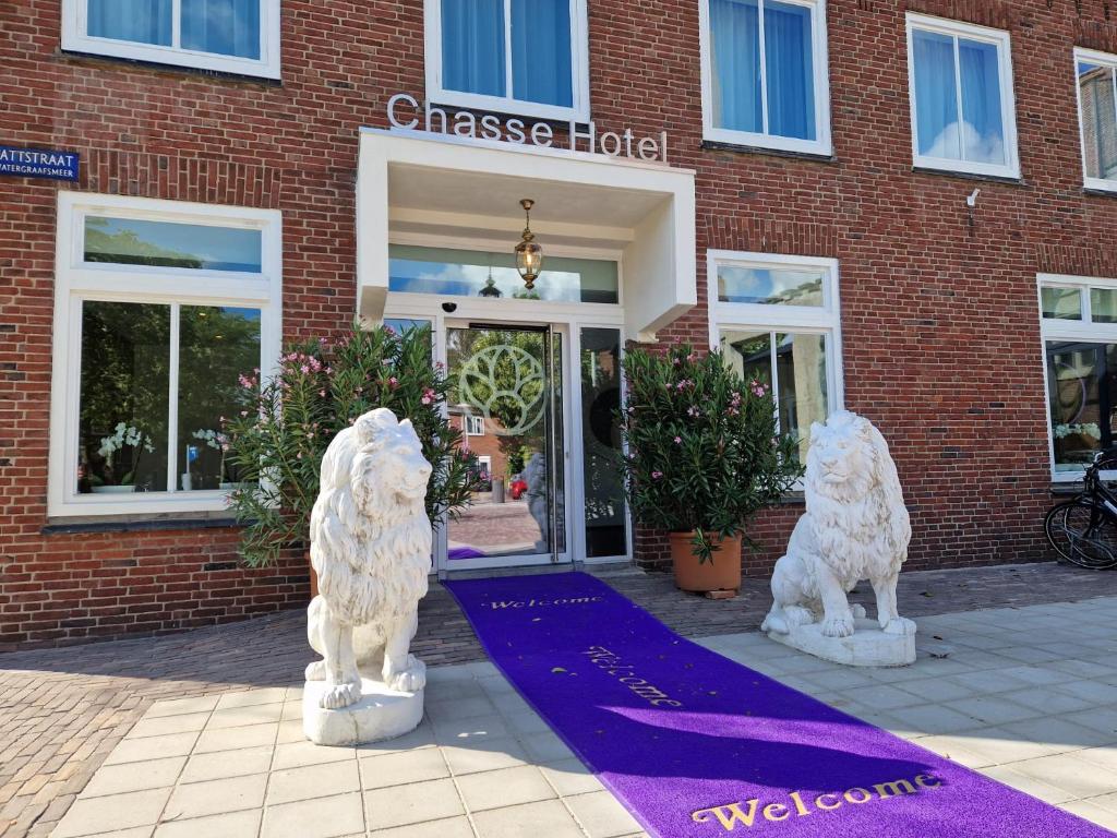 Deux statues blanches de chiens devant un bâtiment dans l'établissement Chassé Hotel Residency, à Amsterdam