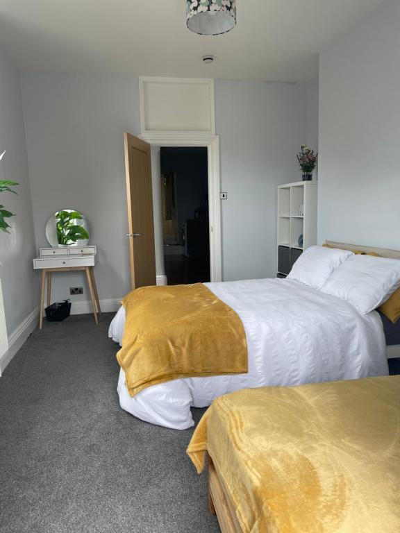 um quarto com 2 camas com lençóis brancos e dourados em Great 2 bedroom flat em Plymouth