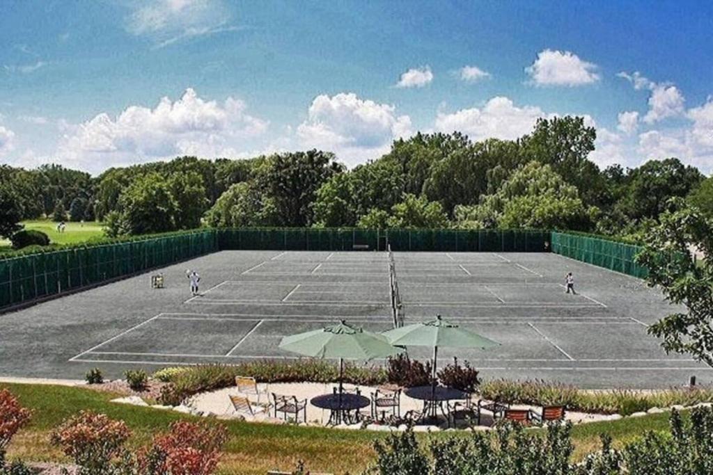 a tennis court with tables and umbrellas on it at Early check in- late check out Free day! in Lake Geneva