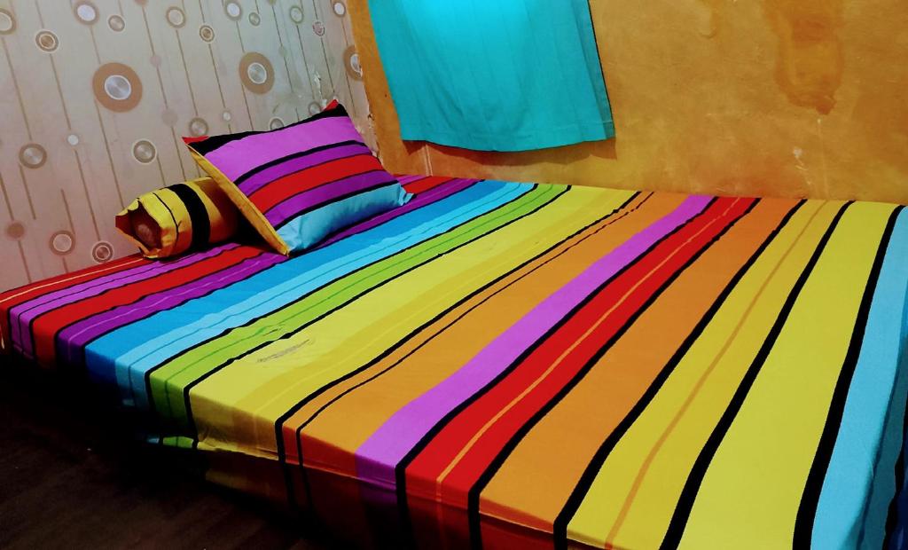 - un lit avec une couette colorée à rayures et un oreiller dans l'établissement Ipol property, à Cisalak