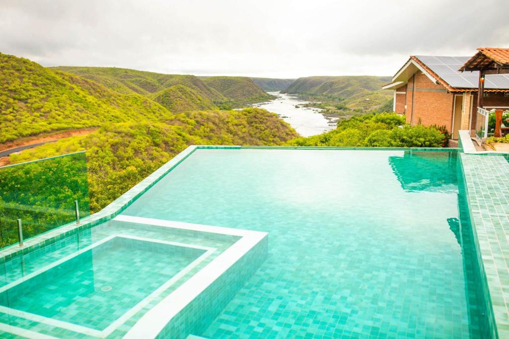 una piscina con vistas al río y a las montañas en Pedra do Sino Hotel, en Piranhas