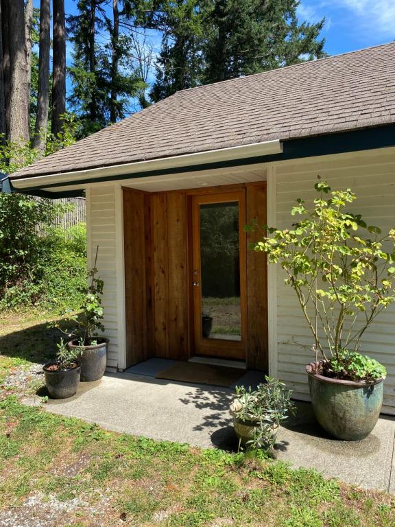 a small shed with a door and two potted plants at Gallery B&B in Ganges