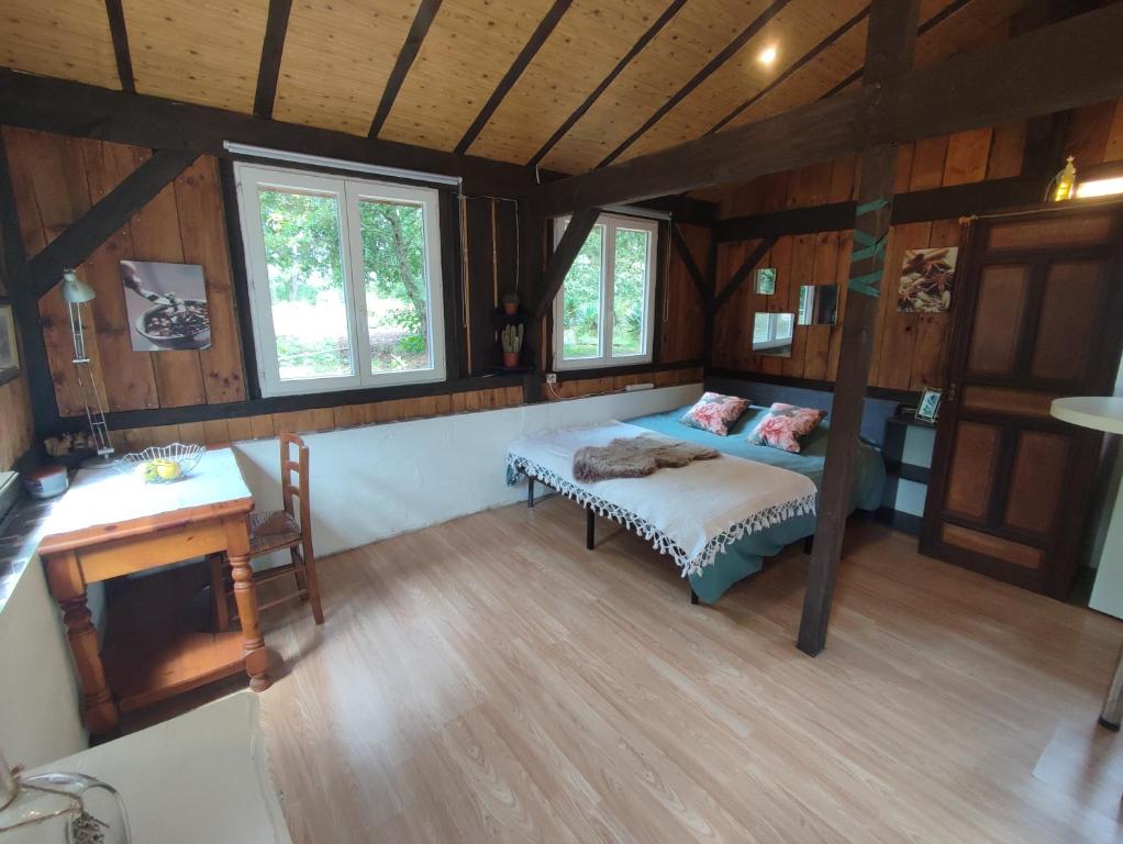 a bedroom with a bed and a desk in a room at La baraque des artistes in Laharie