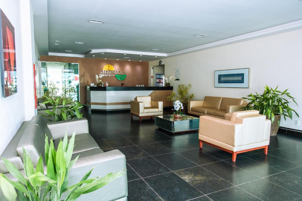 a lobby with couches and plants in a building at Hotel Equinocios Executive in Barcarena
