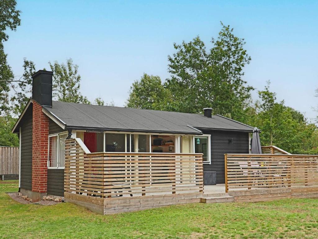 a small house with a wooden fence in a yard at Holiday home STENINGE in Steninge