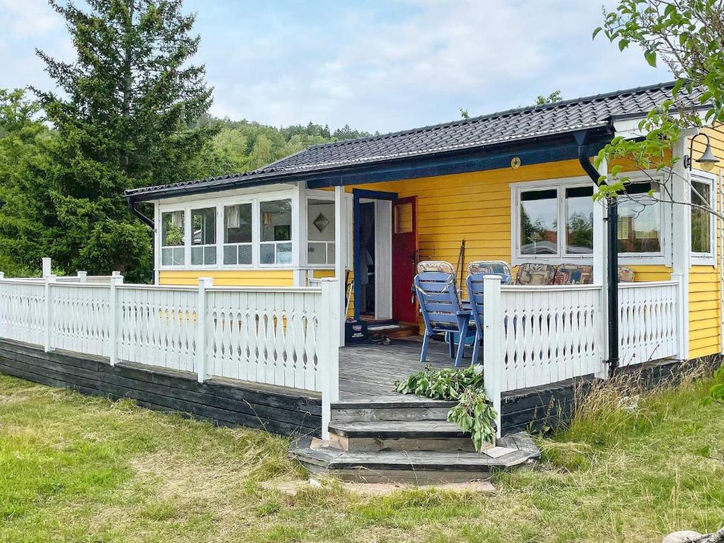 une maison jaune avec une véranda et une clôture blanche dans l'établissement Holiday home KOLMÅRDEN, à Kolmården