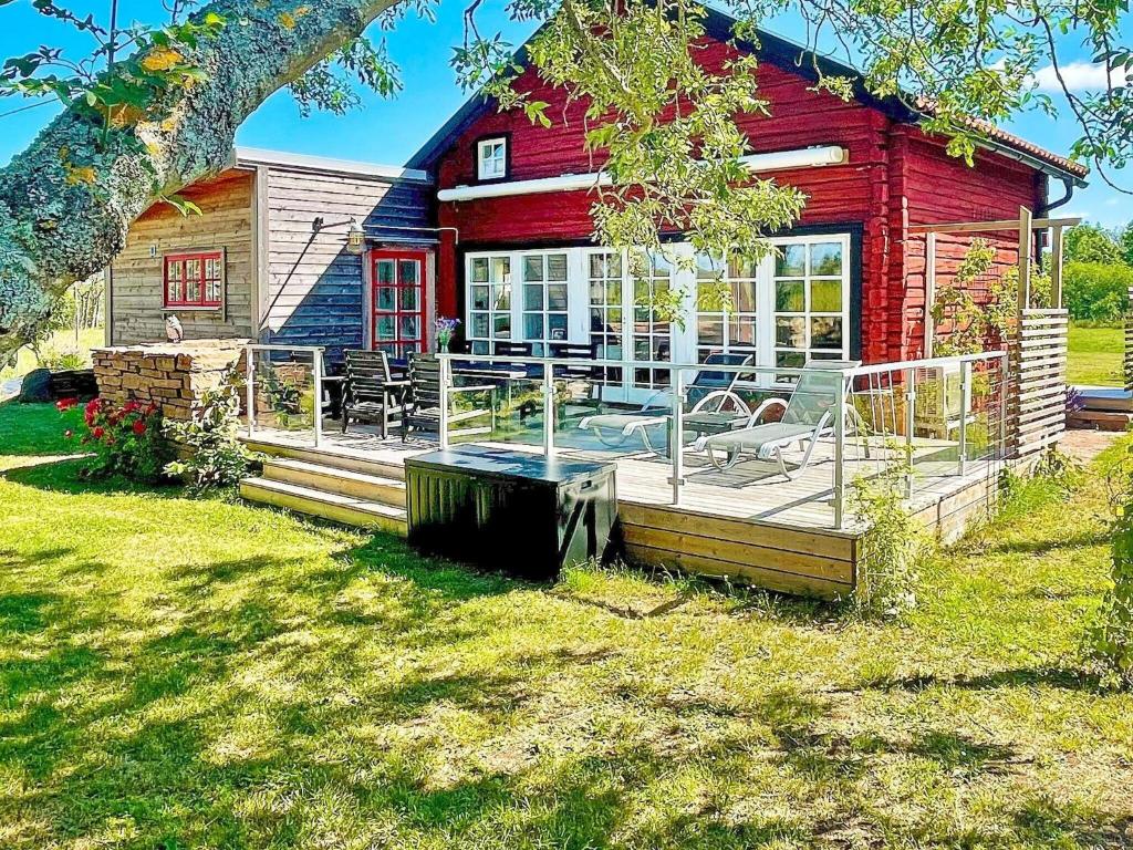 una casa roja con terraza en el patio en Holiday home BORGHOLM XVIII, en Borgholm