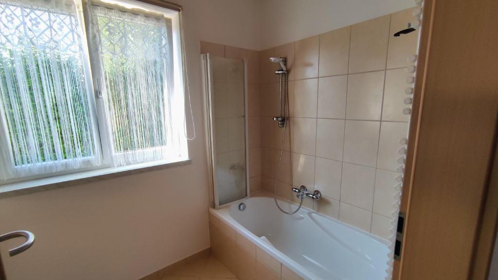 ein Badezimmer mit Badewanne und Fenster in der Unterkunft Hausambalaton in Balatonakali
