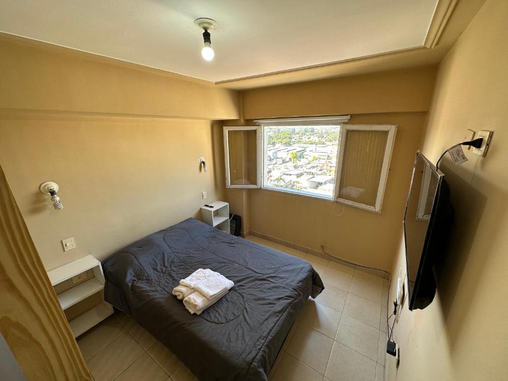 Habitación pequeña con cama y ventana en departamento minimalista en barrio sur en San Miguel de Tucumán
