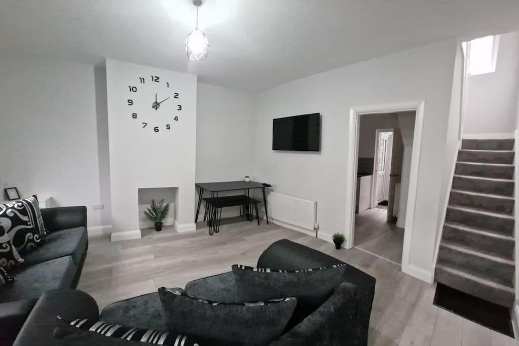 a living room with a couch and a clock on the wall at Modern Belfast City Home in Belfast