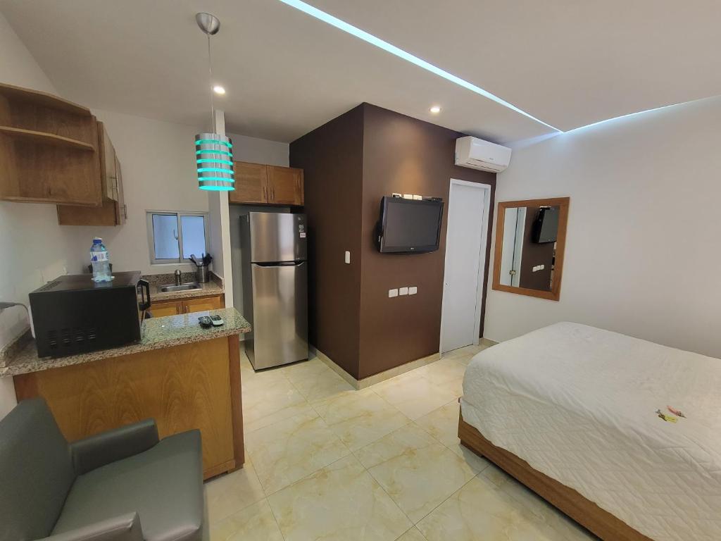 a bedroom with a bed and a kitchen with a refrigerator at Marcel Suites in Santo Domingo