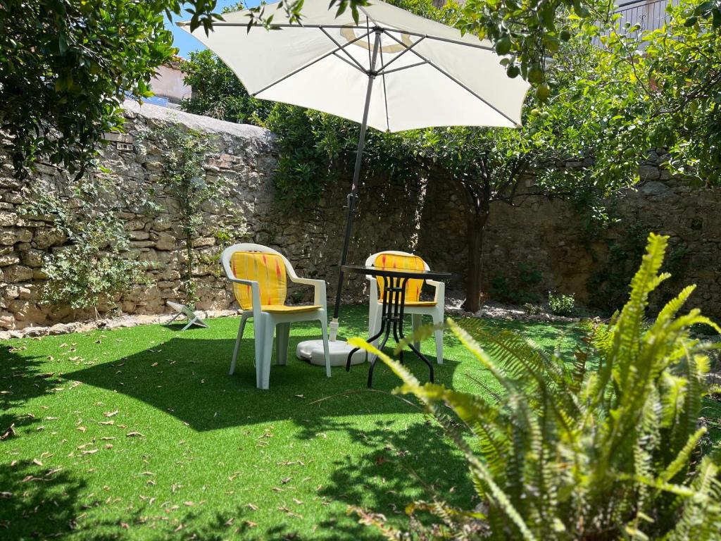 two chairs and a table with an umbrella in a garden at Theoni's Village Apartment II in Kalamata