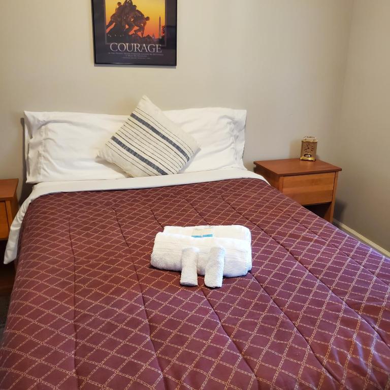 a bed with a purple comforter with two towels on it at Relaxing Stay Near the Beach in Hampton