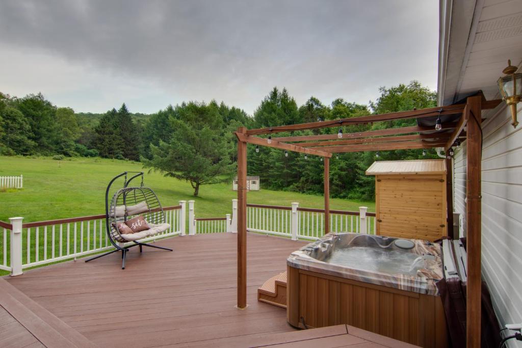 eine Holzterrasse mit einer Schaukel und einem Stuhl darauf in der Unterkunft Coudersport Home with Outdoor Spa and Stargazing! in Coudersport