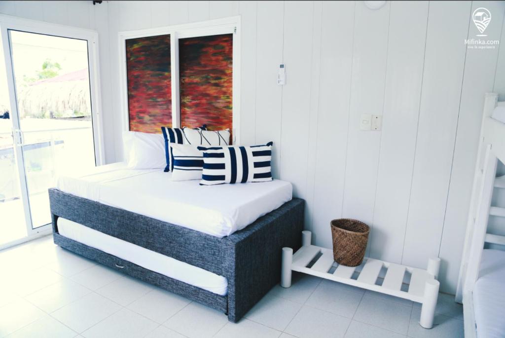 a bedroom with a bed with striped pillows and a window at CABAÑA EL ARBOL CARTAGENA in Cartagena de Indias