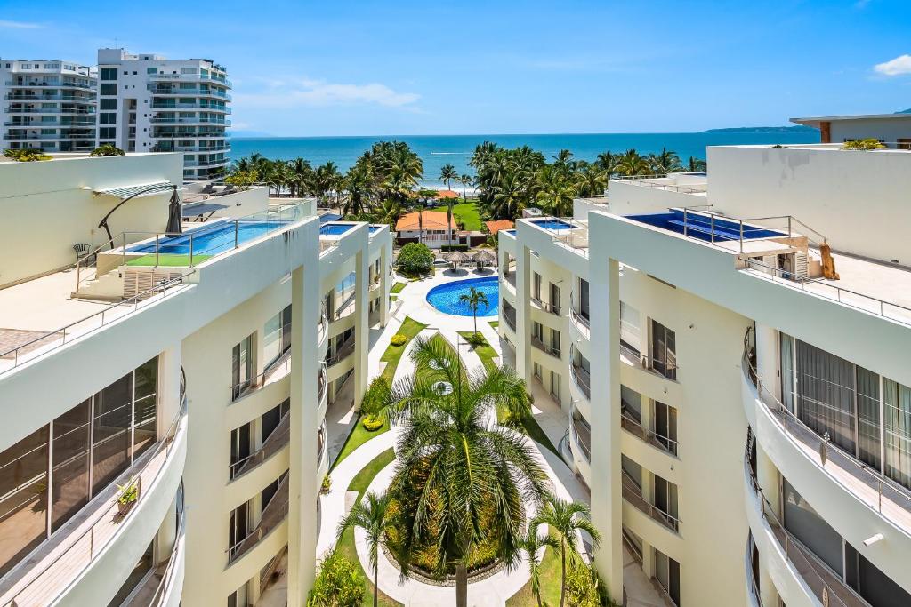 ヌエボ・バジャルタにあるNitta Condo #203のヤシの木と海のある2つの建物の航空写真