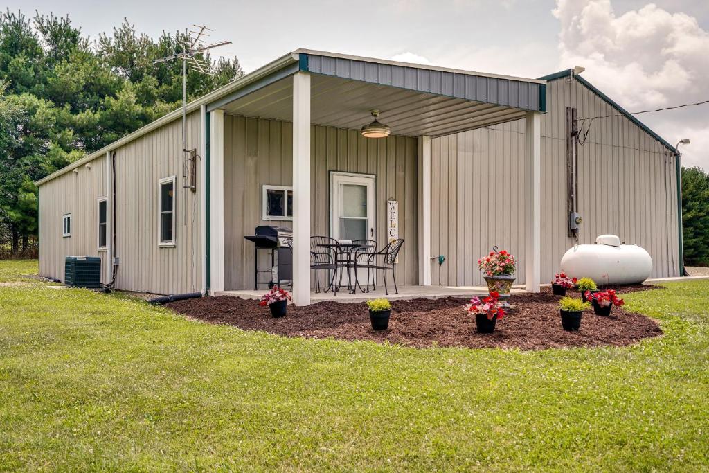 a large metal building with a patio with flowers in a yard at Quaint Somerset Getaway with Fire Pit! in Mount Perry