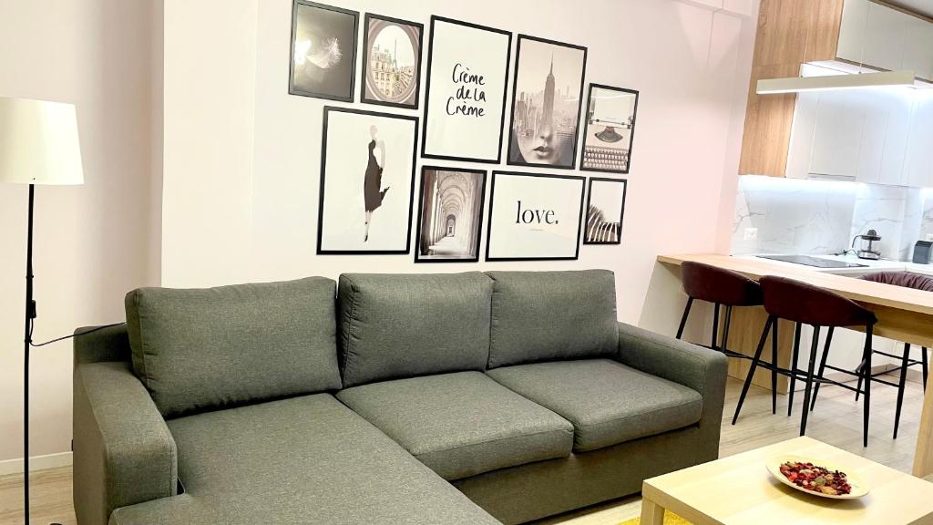 uma sala de estar com um sofá e quadros na parede em Lovely Apartment em Tirana